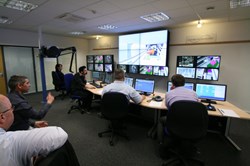 Tasks in the four-person work cell are divided among the responsible officer; the deputy who controls cameras and support tools; the ''mover'' in charge of driving casks, transporters and cranes; and the ''manipulator'' in charge of the master arm and other manipulators. (Click to view larger version...)